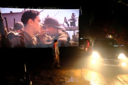 People drive past a cinema screen during a wedding party in Bogor, Indonesia, February 18, 2017. REUTERS/Beawiharta/Files