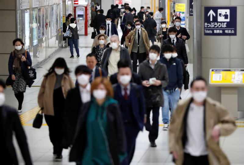 Passengers wearing protective face masks, following an outbreak of the coronavirus disease, walk to work the day before a state of emergency is expected to be imposed at a station in Tokyo