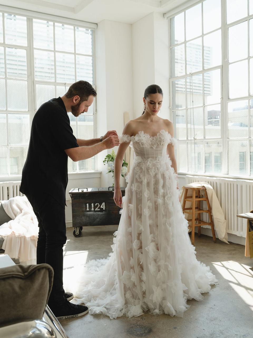 A man makes adjustments to a woman's wedding dress.