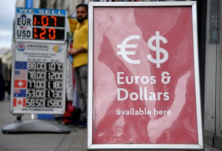 FILE PHOTO: Boards displaying buying and selling rates are seen outside of currency exchange outlets in London