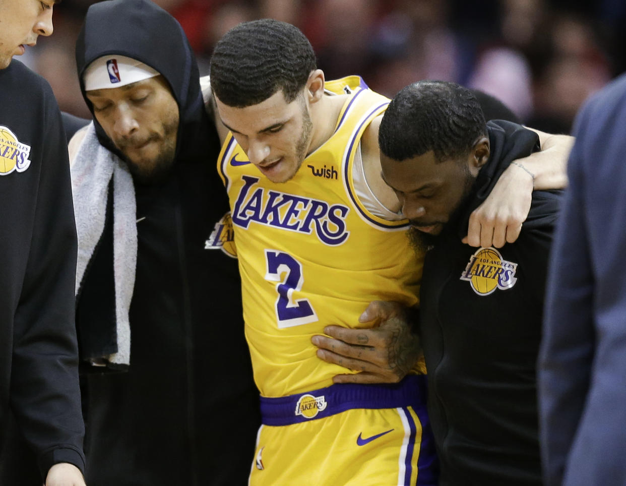 Los Angeles Lakers guard Lonzo Ball (2) is carried off the court by Michael Beasley, left, and Lance Stephenson after Ball sustained an injury during the second half of an NBA basketball game against the Houston Rockets, Saturday, Jan. 19, 2019, in Houston. (AP Photo/Eric Christian Smith)