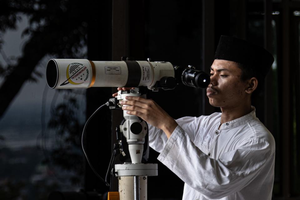 An Indonesian Muslim uses binoculars to look at the new crescent moon, marking the end of Ramadan.