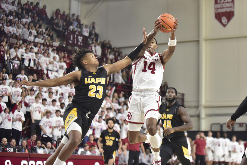Oklahoma forward Jalon Moore (14) grabs a rebound over Arkansas-Pine Bluff guard Lonnell Martin Jr (23) during the first half of an NCAA college basketball game in Norman, Okla., Thursday, Nov. 30, 2023. (AP Photo/Kyle Phillips)