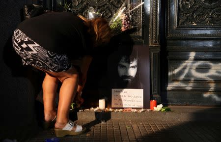 A woman places flowers next to a portrait of Santiago Maldonado, a protester who went missing since security forces clashed with indigenous activists in Patagonia on August 1, 2017, at the entrance of a judicial morgue in Buenos Aires, Argentina October 20, 2017. REUTERS/Marcos Brindicci