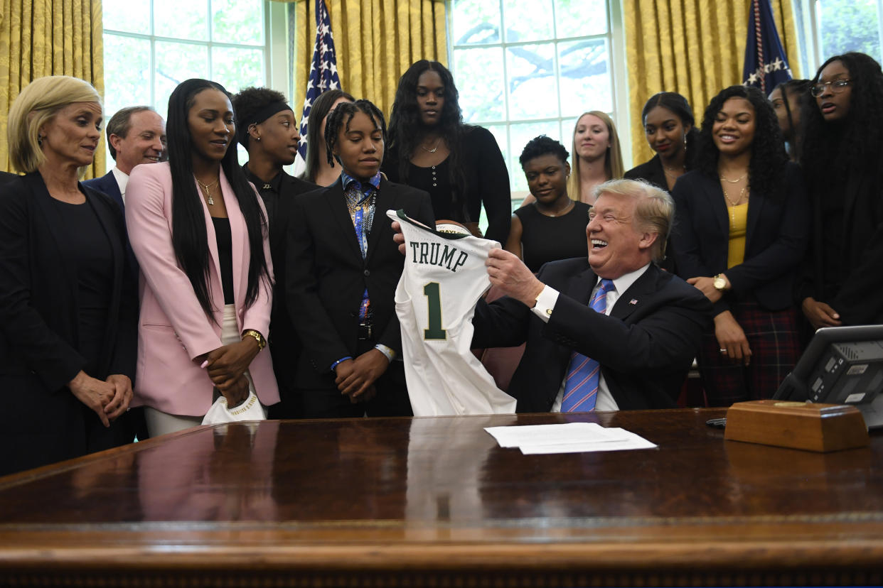 President Donald Trump holds up a jersey that was presented to him as he welcomed members of the Baylor women's basketball team, who are the 2019 NCAA Division I Women's Basketball National Champions, to the Oval Office of the White House in Washington, Monday, April 29, 2019. Baylor women's basketball head coach Kim Mulkey, left, watches. (AP Photo/Susan Walsh)