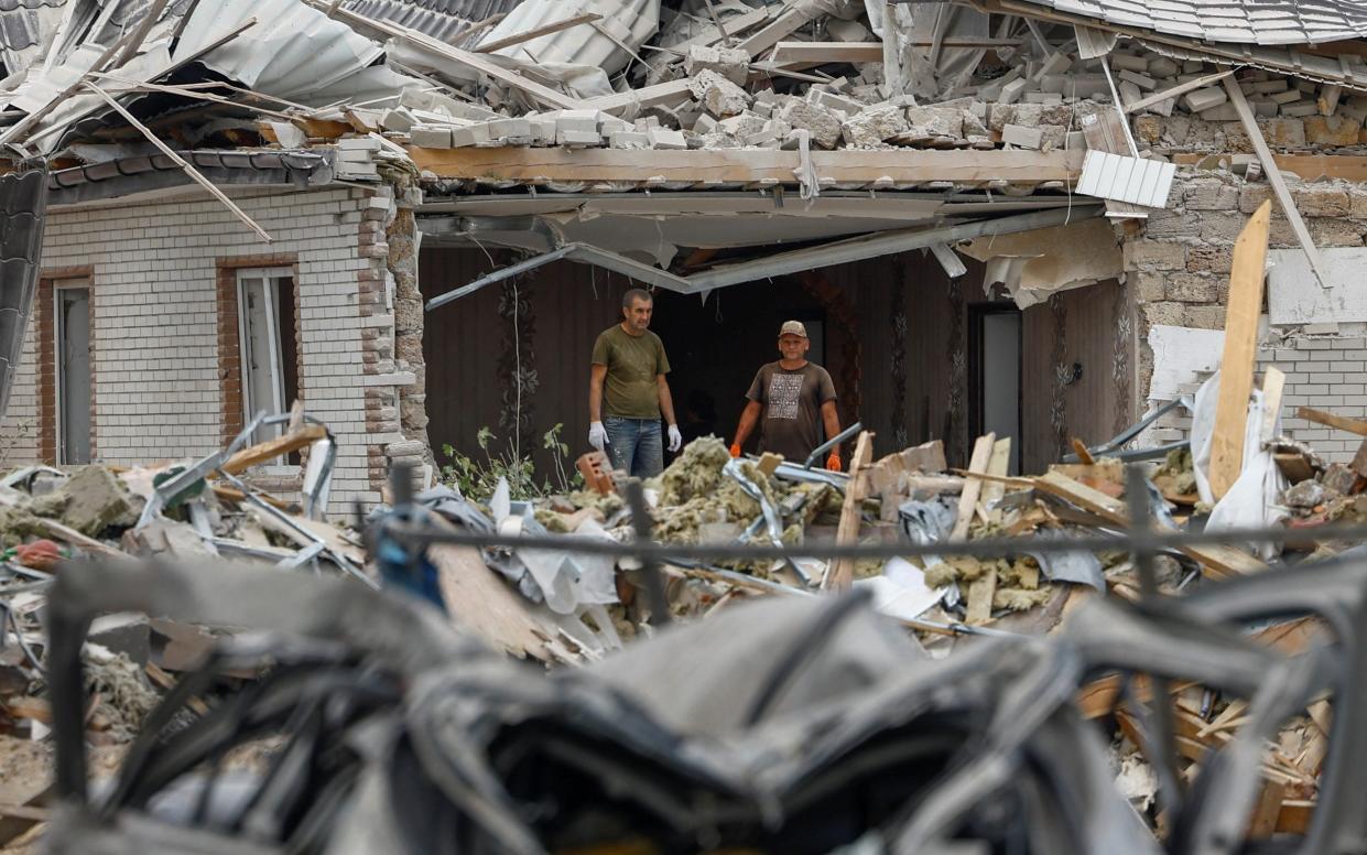 Ukrainian men survey the damage in the village of Rozhivka