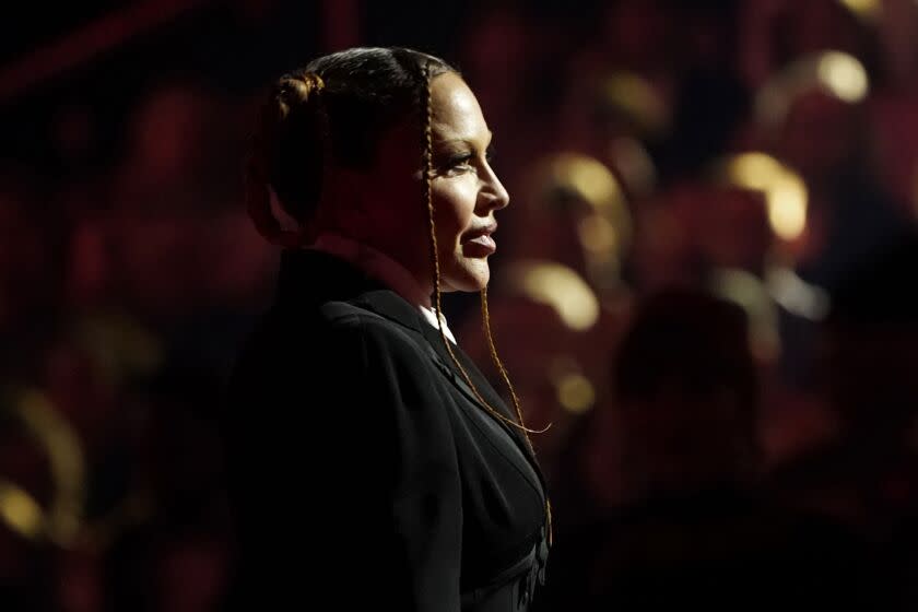 A woman is seen in profile on a darkened stage