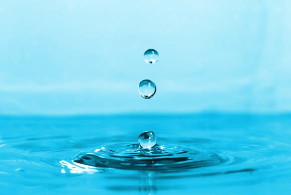 Three water droplets falling into a body of water and creating ripples.