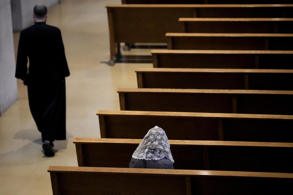 A woman sits alone before Catholic Mass at Benedictine College Sunday, Oct. 29, 2023, in Atchison, Kan. (AP Photo/Charlie Riedel)