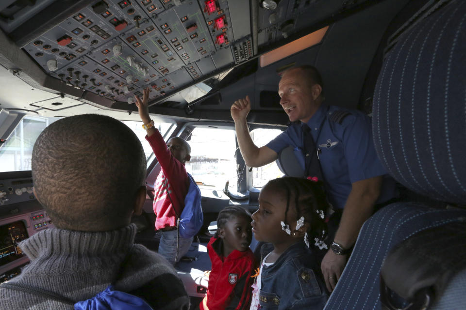 Captain Paul Bruder, right, show a group of children the cockpit, Saturday, Sept. 21, 2013 while the aircraft was parked on the tarmac at JFK airport in New York. Dozens of families with children with autism have practiced air travel at New York's Kennedy International Airport. JetBlue Airways and the nonprofit Autism Speaks held the practice run for families at JFK on Saturday. (AP Photo/Mary Altaffer)