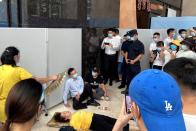 A woman receives aid on the ground next to Du Liang, general manager and legal representative of Evergrande's wealth management division, in Shenzhen