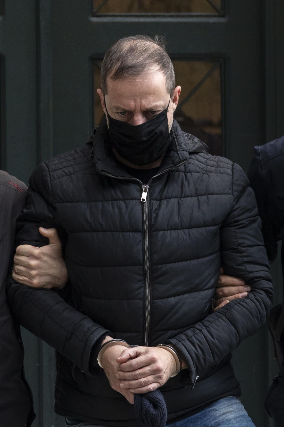 Handcuffed actor and director Dimitris Lignadis, leaves a magistrate's office in Athens, Sunday, Feb. 21, 2021. Lignadis, 56, the former artistic director of Greece's National Theatre, has been arrested on rape charges, police say. (AP Photo/Yorgos Karahalis)