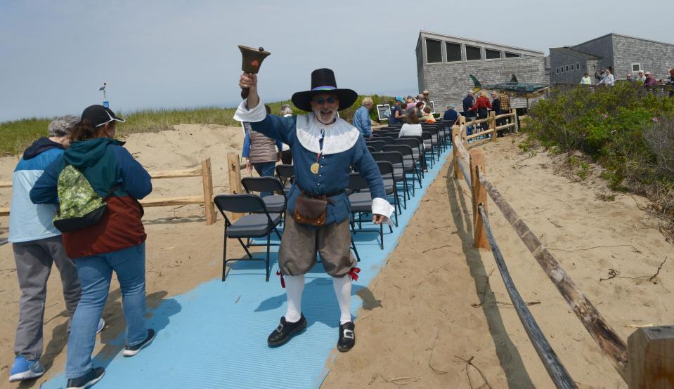 Provincetown Town Crier Daniel Gomez Llata rings in the crowd for the start of a ceremony to unveil a new shark sculpture at Herring Cove Beach in Provincetown on Thursday, World Ocean Day.