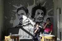 People sit in a coffee shop as cafes, restaurants and other eateries reopened in some provinces across the country, in Ankara, Turkey, Wednesday, March 3, 2021. The businesses are allowed to operate at half-capacity between the hours of 7:00 a.m. and 07:00 p.m. as coronavirus restrictions are eased. (AP Photo/Burhan Ozbilici)