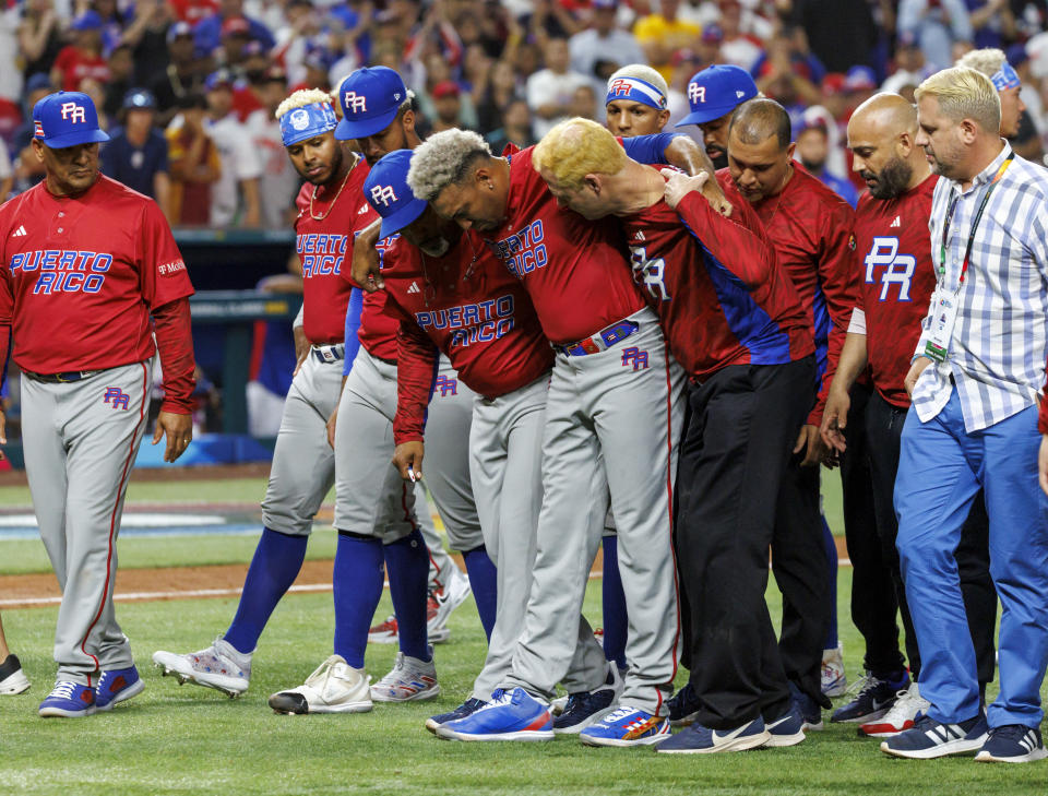 El pitcher puertorriqueño Edwin Díaz (39) recibe auxilio del coach Ricky Bones y el personal médico tras lesionarse en un juego contra la República Dominicana, el miércoles 15 de marzo de 2023, en Miami. (David Santiago/Miami Herald vía AP)