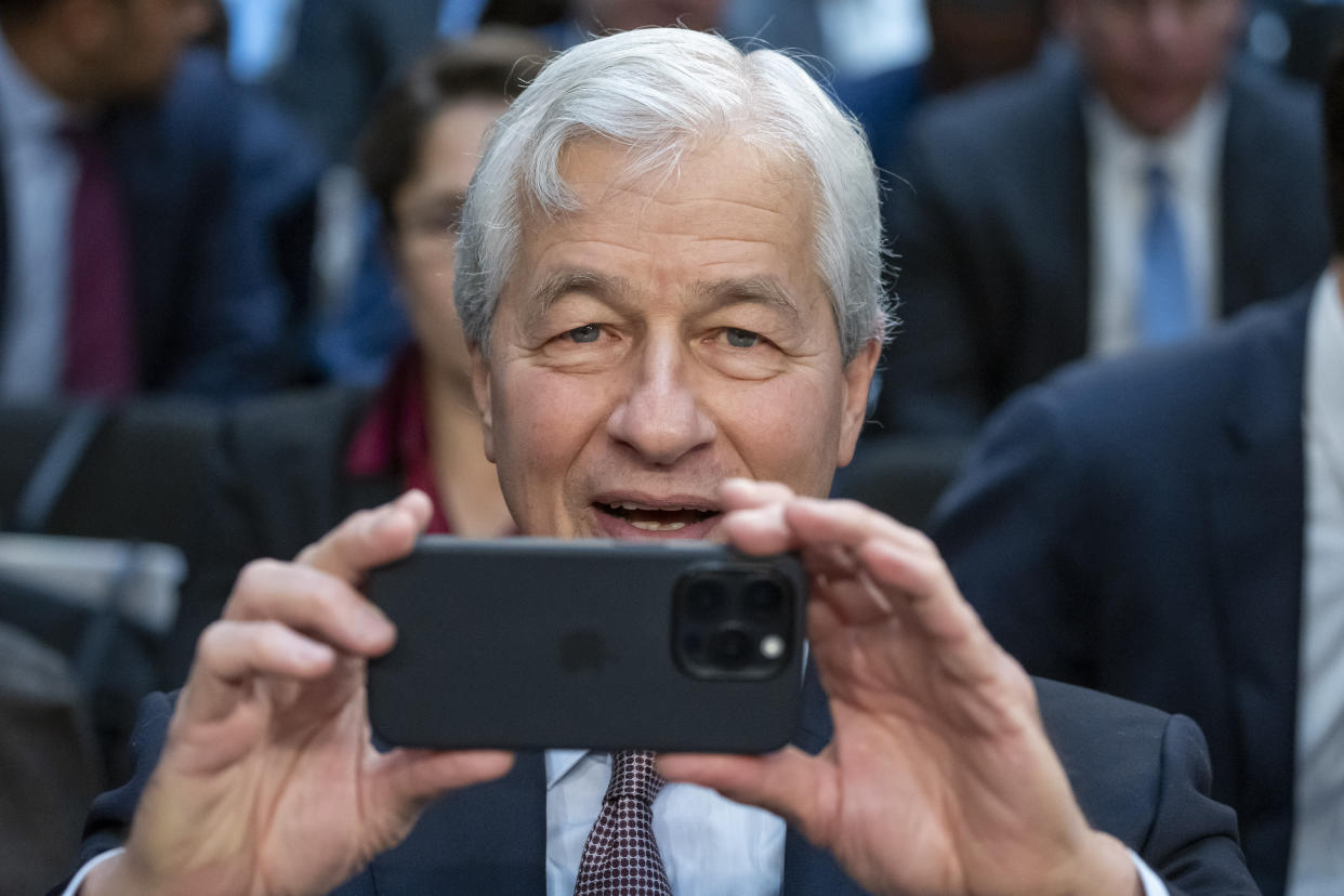 Jamie Dimon, Chairman and CEO of JPMorgan Chase & Co., takes a photo of journalists before a Senate Banking, Housing, and Urban Affairs Committee oversight hearing to examine Wall Street firms on Capitol Hill, Wednesday, Dec. 6, 2023, in Washington. (AP Photo/Alex Brandon)