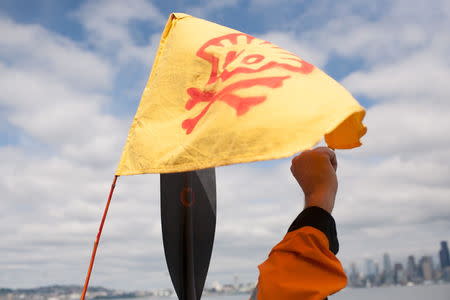 A protester raises a fist near a flag, demonstrating against Shell Oil's Polar Pioneer rig as it arrives in Seattle, Washington, May 14, 2015. REUTERS/Matt Mills McKnight