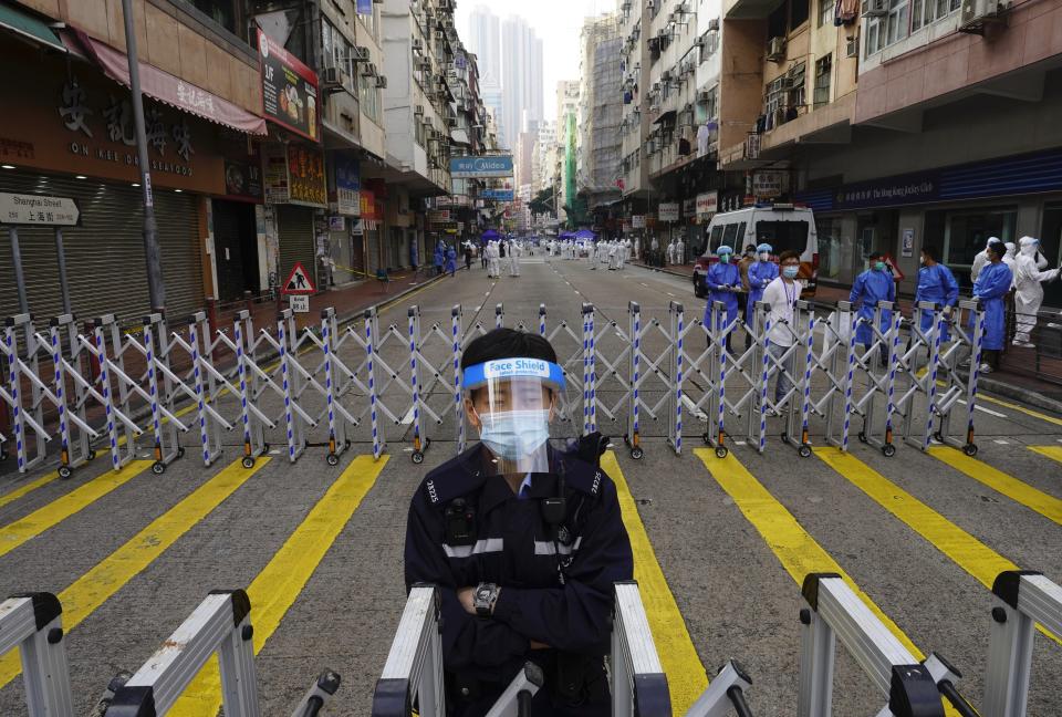 A police officer stands guard at the Yau Ma Tei area, in Hong Kong, Saturday, Jan. 23, 2021. Thousands of Hong Kong residents were locked down Saturday in an unprecedented move to contain a worsening outbreak in the city, authorities said. (AP Photo/Vincent Yu)