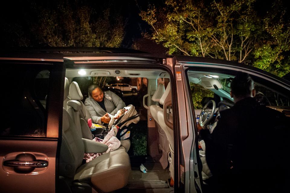 A women unbuckles a baby from a carseat in an SUV.