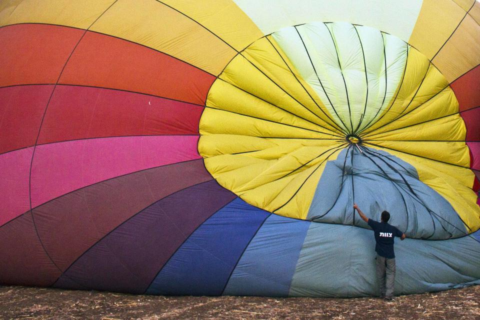 A man prepares a hot air balloon before it takes flight during a two-day festival near Mount Gilboa in northern Israel September 23, 2013. (REUTERS/Nir Elias)