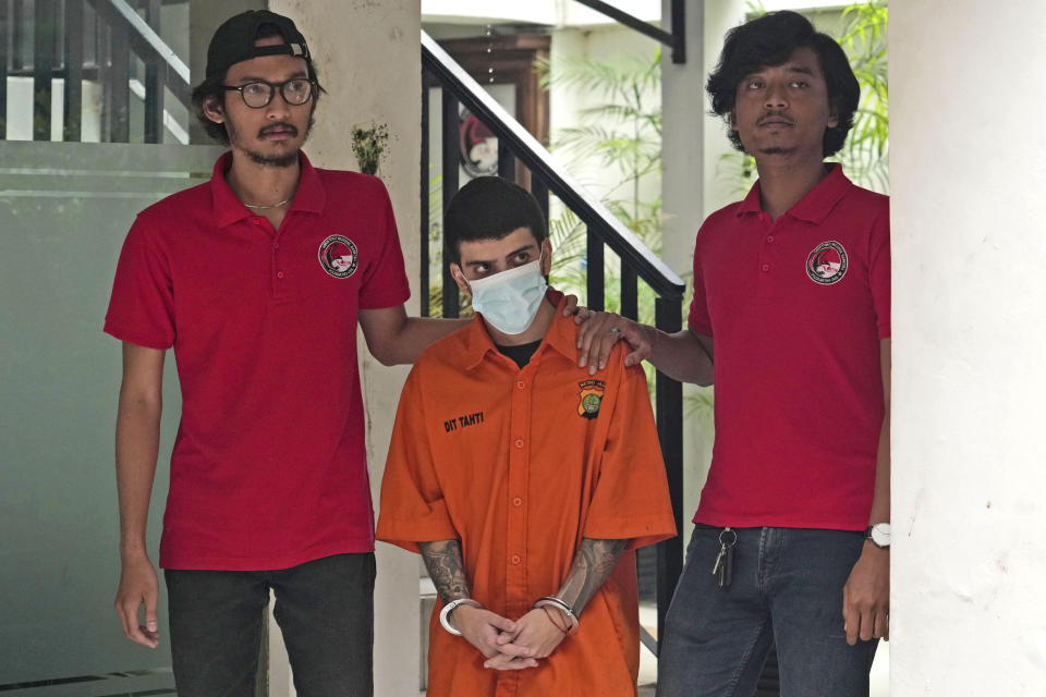 Plain-clothed police officers escort Brazilian national Gustavo Pinto da Silveira, center, prior to a press conference at the regional police headquarters in Jakarta, Indonesia, Wednesday, March 15, 2023. Indonesian authorities said Wednesday they have arrested four foreigners who allegedly tried to smuggle drugs into the country's capital, including da Silveira who was caught with 2 liters (67.6 ounces) of liquid cocaine while arriving from Rio de Janeiro in January, and a Nigerian man who had swallowed dozens of capsules filled with more than a kilogram (2.2 pounds) of methamphetamine. (AP Photo/Tatan Syuflana)