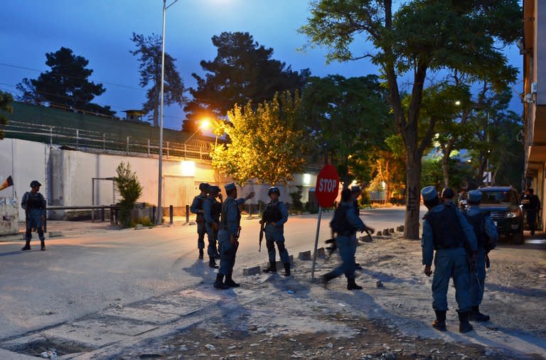 Afghan policemen stand guard near the site of a clash between security forces and Taliban fighters in Kabul on May 24, 2013