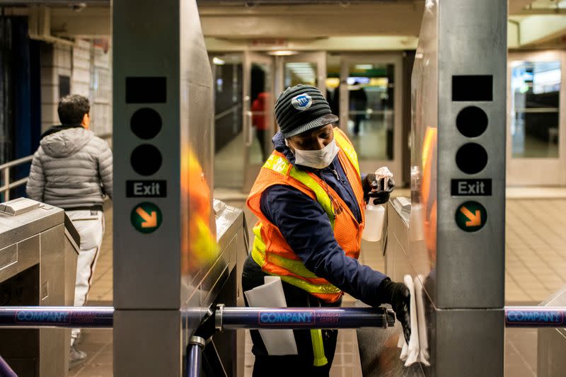 FILE PHOTO: An MTA transit worker cleans a nearly empty Times Square - 42nd street subway station following the outbreak of coronavirus disease (COVID-19) in New York City