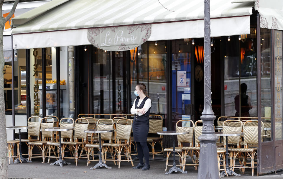 PARIS, FRANCE - OCTOBER 22: A waitress wearing a protective face mask waits for customers in front of an empty restaurant terrace near Notre-Dame Cathedral during the coronavirus outbreak on October 22, 2020 in Paris, France. In the absence of tourists due to the coronavirus pandemic (COVID 19) and measures taken by the French government to curb the disease, many bars, restaurants and souvenir shops are empty in tourist sites in the capital. (Photo by Chesnot/Getty Images)