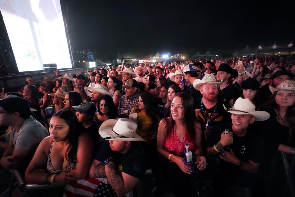 Fans listen as Parker McCollum performs with his band at Country Thunder Music Festival in Florence, Arizona on April 15, 2023. McCollum was also booked for Country Thunder in Twin Lakes, Wisconsin this month. On Thursday, Milwaukee TV news reporter Taylor Lumpkin tweeted that she was called a racist slur while covering the event.