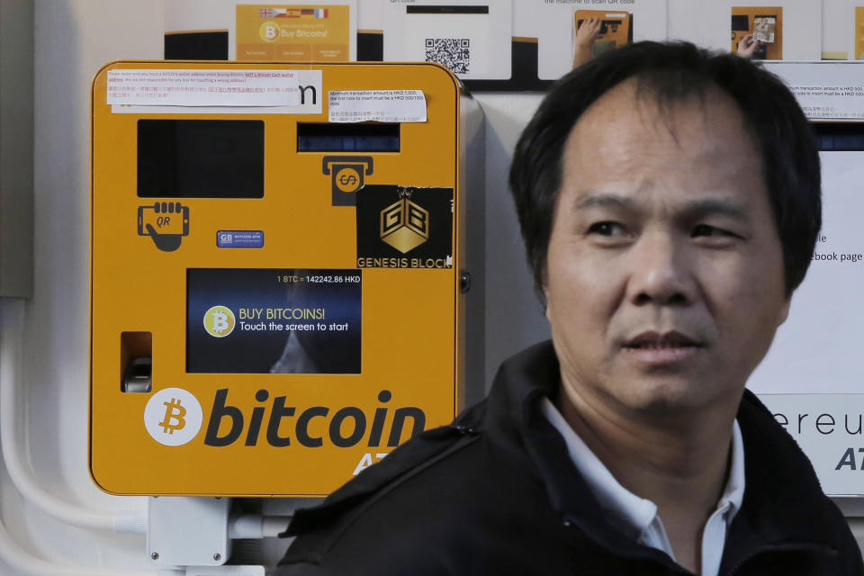 A man walks past the Bitcoin ATMs in Hong Kong, Thursday, Dec. 21, 2017. (AP Photo/Kin Cheung)