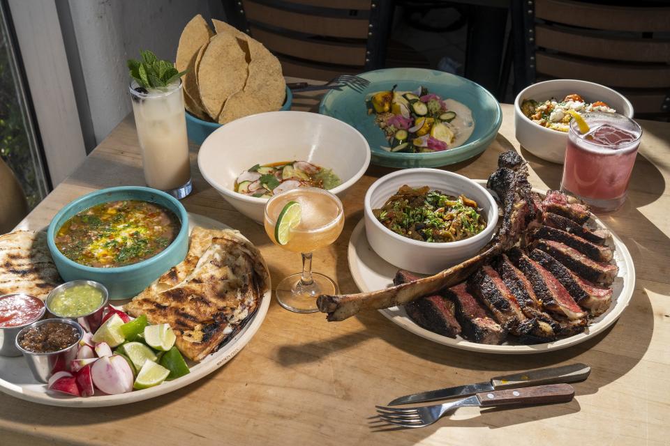 An assortment of dishes and drinks at Bacanora including a tomahawk steak, aguachile, quesadillas, cucumber salad, warm calabaza, tamarind honey daiquiri, margarita, and La Chareauna on Wednesday, March 2, 2022, in Phoenix.