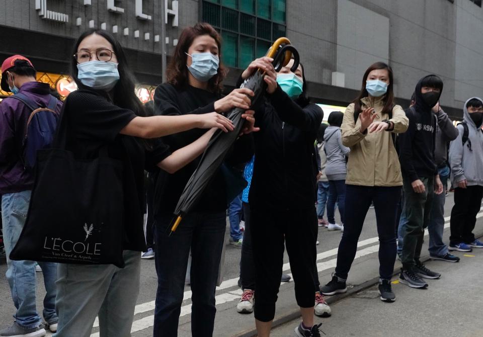 Protestors pass on umbrellas to front line protestors during their annual pro-democracy march on New Year's Day in Hong Kong, Wednesday, Jan. 1, 2020. Hong Kong toned down its New Year’s celebrations amid the protests that began in June and which have dealt severe blows to the city’s retail, tourism and nightlife sectors. (AP Photo/Vincent Yu)