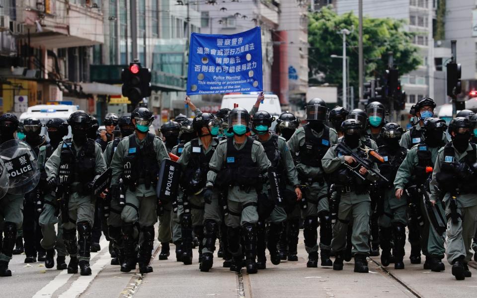 Riot police officers walk as anti-national security law protesters march in 2019  - Reuters