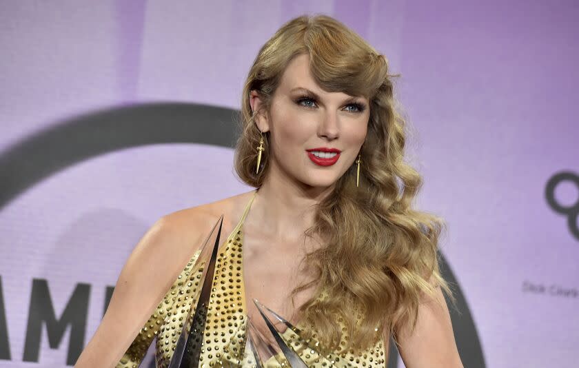 A woman with long, curly blond hair wearing a bedazzled dress and holding a clear, pointy trophy