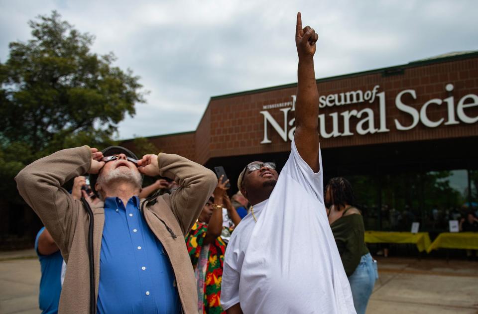 Bob Garner, left, and Antwan Waters, right, watch the solar eclipse during an event at the Mississippi Museum of Natural Science in Jackson, on Monday. "Unfortunately, the clouds kind of obscured a lot of it," Garner said. "I got a couple of good glimpses."