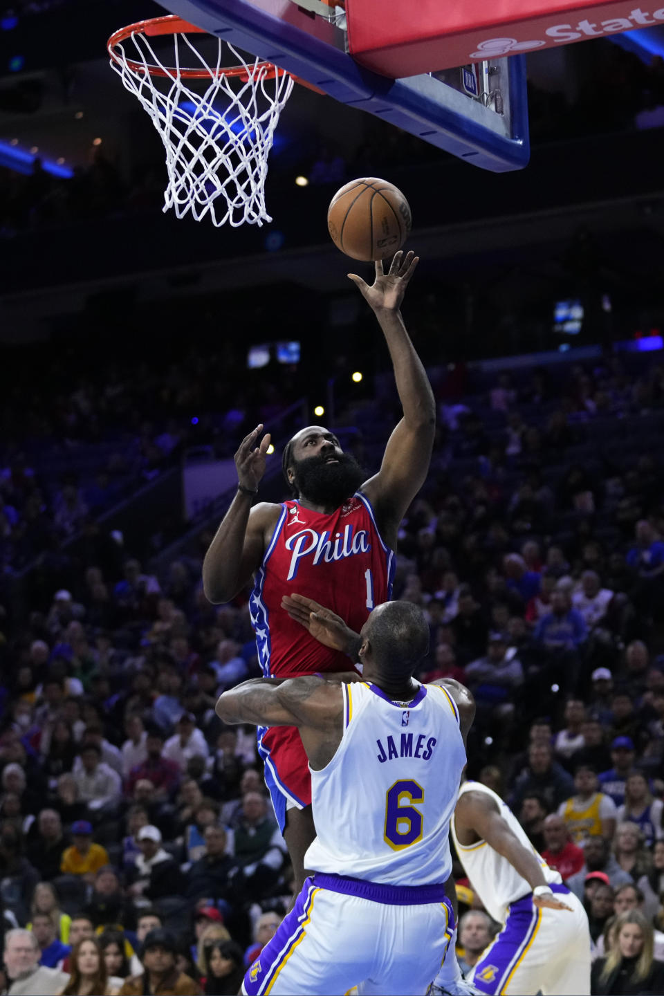 Philadelphia 76ers' James Harden (1) goes up for a shot against Los Angeles Lakers' LeBron James (6) during the first half of an NBA basketball game, Friday, Dec. 9, 2022, in Philadelphia. (AP Photo/Matt Slocum)