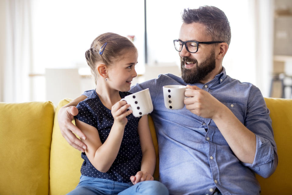 Daughter and father cheersing cup, scheming something. (Getty Images)