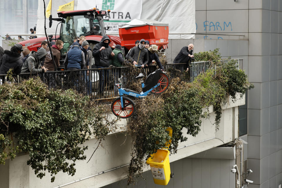 Protestors throw objects off of a small overpass during a demonstration of farmers near the European Council building in Brussels, Tuesday, March 26, 2024. Dozens of tractors sealed off streets close to European Union headquarters where the 27 EU farm ministers are meeting to discuss the crisis in the sector which has led to months of demonstrations across the bloc. (AP Photo/Geert Vanden Wijngaert)