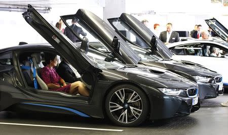 The world's first eight customers of the new BMW i8 plug-in hybrid sports car receive instructions during an official delivery in Munich in this June 5, 2014 file photo. REUTERS/Michaela Rehle/Files