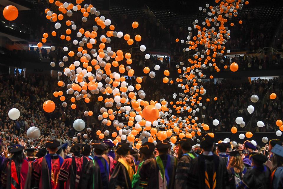 Orange, white and silver balloons fall onto new University of Tennessee at Knoxville graduates.