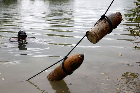 A diver from a bomb-disposal unit looks at unexploded shells recovered in the Meuse River at Sivry-sur-Meuse, close to WW1 battlefields, France, October 24, 2018 before the centennial commemoration of the First World War Armistice Day. REUTERS/Pascal Rossignol