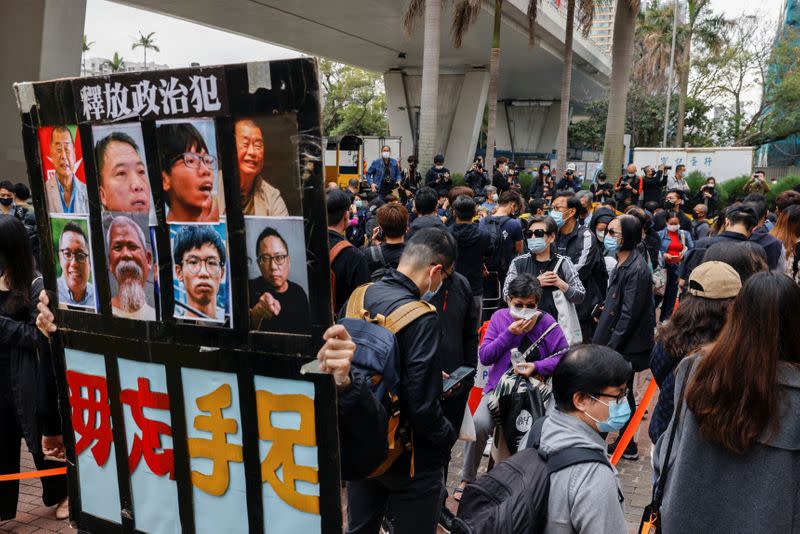 A supporter holds a sign with photos of pro-democracy activists while queuing up for the court hearing over national security law outside West Kowloon Magistrates' Courts, in Hong Kong