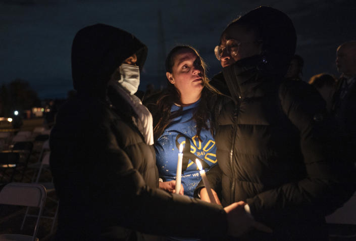 People comfort each other during a candlelight vigil for the people killed at a Walmart in Chesapeake, Va., when a manager opened fire with a handgun before an employee meeting last week, at Chesapeake City Park in Chesapeake, Va., Monday, Nov. 28, 2022. (AP Photo/Carolyn Kaster)