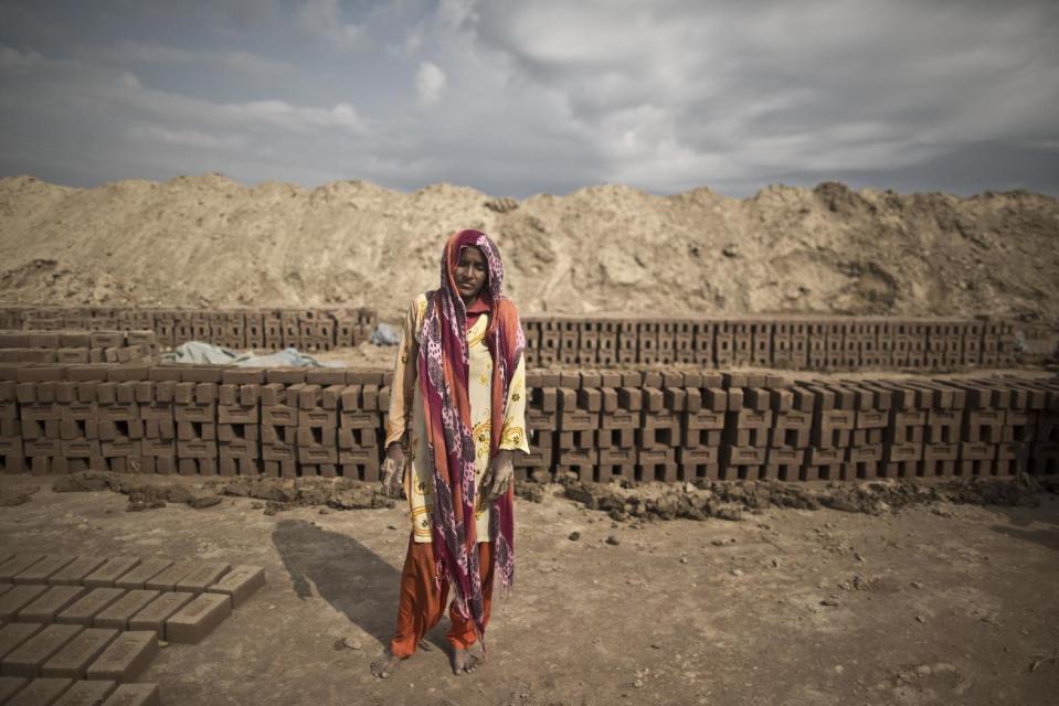 In this Wednesday, March 5, 2014, photo, Raina Anwar, 24, a Pakistani brick factory worker, poses for a picture at the site of her work in Mandra, near Rawalpindi, Pakistan. Raina and her husband are in debt to their employer the amount of 190,000 rupees (approximately $1900).(AP Photo/Muhammed Muheisen)