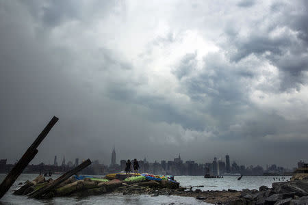 Two people walk on painted rocks, as a large storm looms over the skyline of New York June 3, 2014. REUTERS/Lucas Jackson