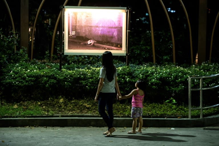 Churchgoers look at an exhibit of pictures showing the deaths of alleged drug dealers and users outside Baclaran Church in Manila