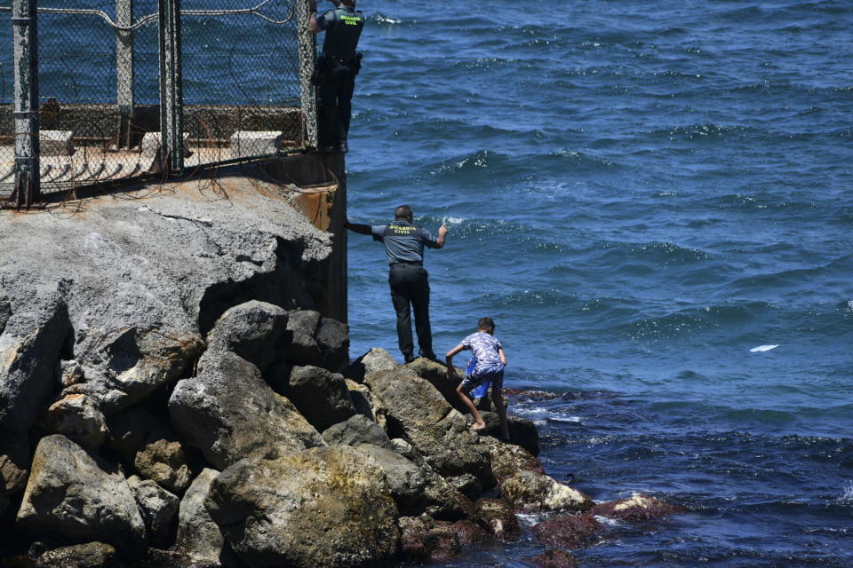 Spanish Guardia Civil officer try to stop people from Morocco entering into the Spanish territory at the border of Morocco and Spain, at the Spanish enclave of Ceuta on Monday, May 17, 2021. Authorities in Spain say that around 1,000 Moroccan migrants have crossed into Spanish territory (Antonio Sempere/Europa Press via AP)