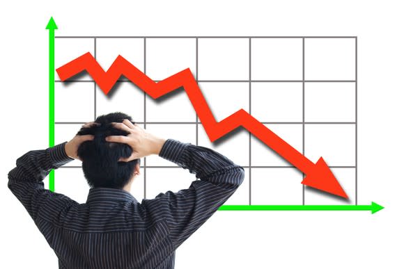 A person staring at a red arrow on graph trending sharply downward.