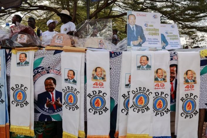 People walk past stalls selling accessories bearing the image of Paul Biya, President of the Republic of Cameroon, to mark the 40th anniversary of Biya's rule in Yaounde on November 6, 2022. - Biya has served as president since November 6, 1982.