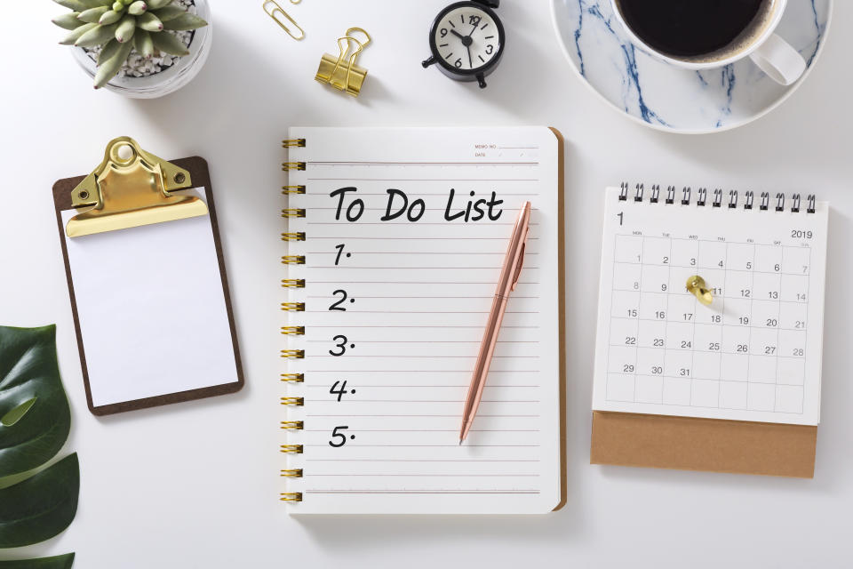 To do list in notebook with calendar and clock on white desk